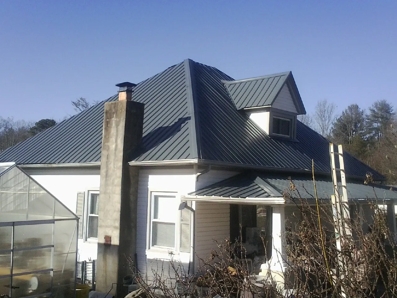 Dark blue standing seam metal roof on a white farmhouse with dormer — Slate & Tile Roof Repair by Roofing Brothers in Stendal