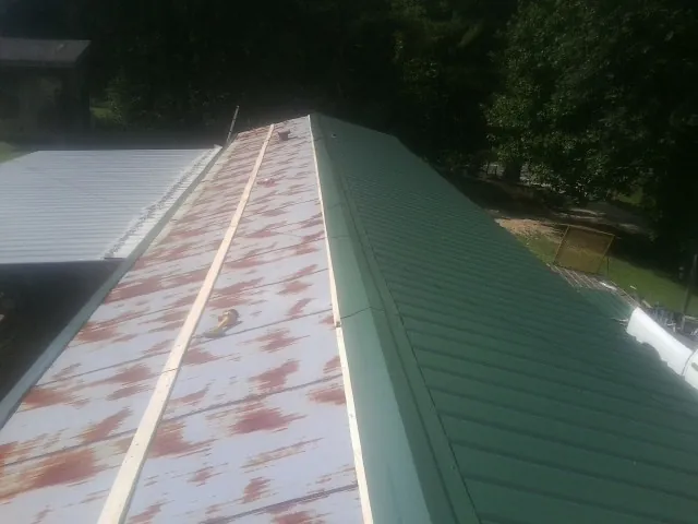 Old rusted panels beside newly installed green metal roofing — Wind Damage Roof Repair by Roofing Brothers in Stendal
