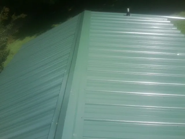 New green metal panels meeting at the ridge of a roof — Flat Roof Repair work by our crew in Stendal