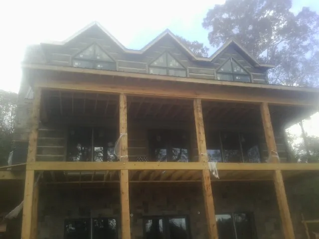 Dormers and porch framing on a large log home under construction — Roof Coating work by our crew in Stendal