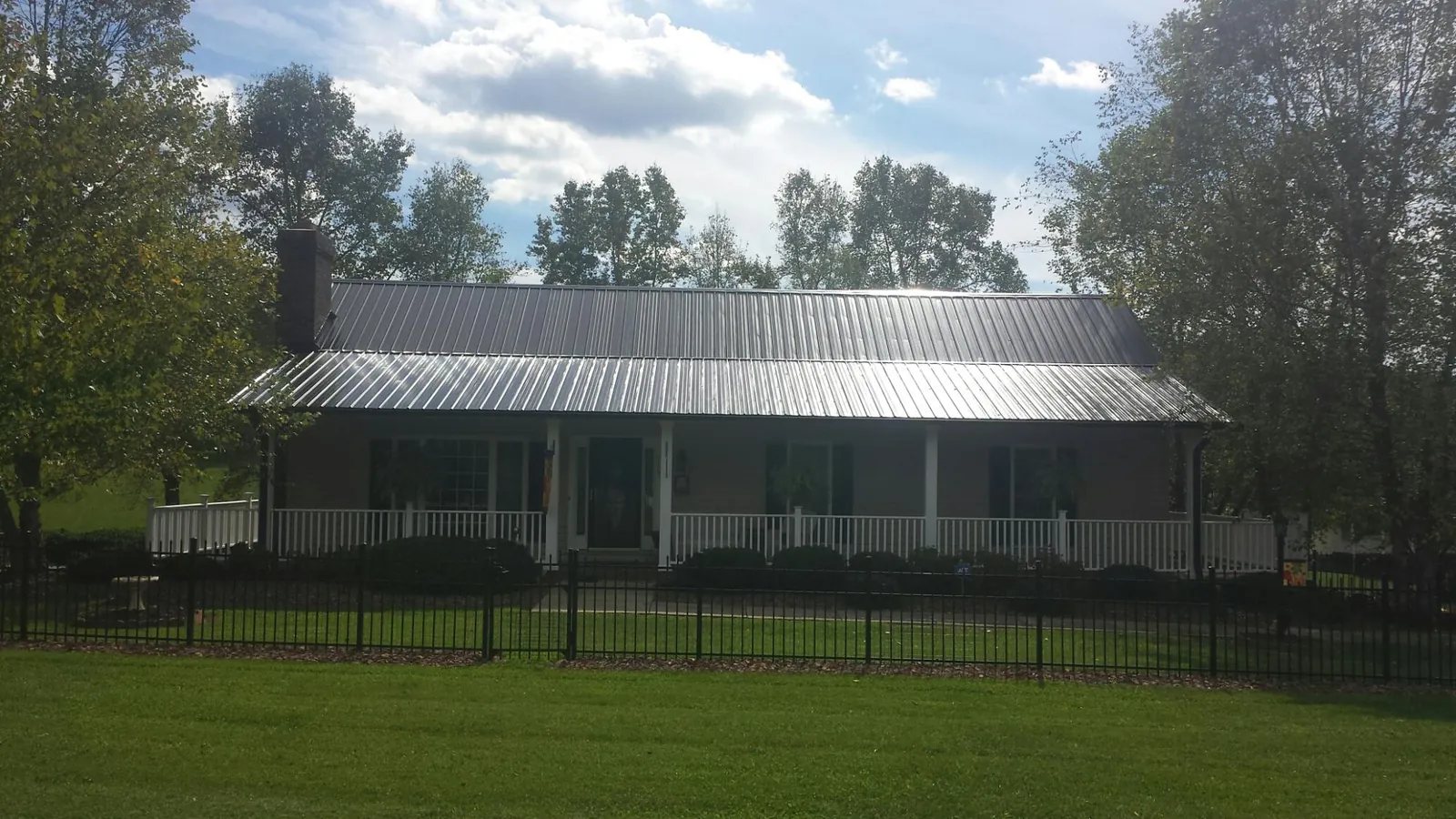 Gray metal roof on a brick ranch with a full width front porch — Gutter Guard Installation work by our crew in Stendal
